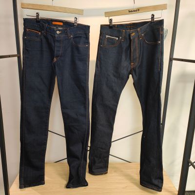 deux paires de jeans suspendues à un portant dans un magasin de vêtements