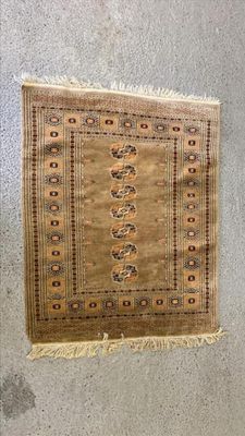 tapis accroché au mur dans une pièce où se trouvent une chaise et une table