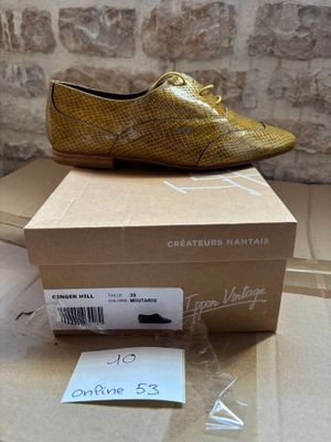 yellow snake skin shoes on top of a cardboard box on a table