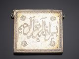 an old silver plaque with arabic writing on it on a black background