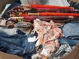 a cardboard box full of clothes and umbrellas on the floor
