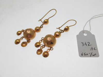 une paire de boucles d'oreilles dorées ornées de perles pendantes et d'une étiquette de prix