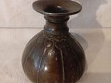 un vase marron posé sur un tissu blanc