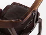 a wooden chair with a brown leather seat and arm rest