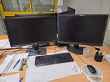 deux écrans d'ordinateur posés sur un bureau, à côté d'un clavier et d'une souris