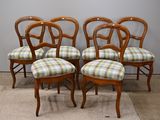quatre chaises en bois aux assises recouvertes d'un tissu à carreaux, devant un mur gris