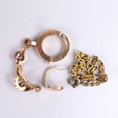 une chaîne en or et une paire de boucles d'oreilles posées sur une surface blanche