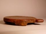 a wooden cutting board with a wooden handle on a table