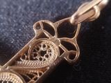 a close up of a gold pendant with a clock on it