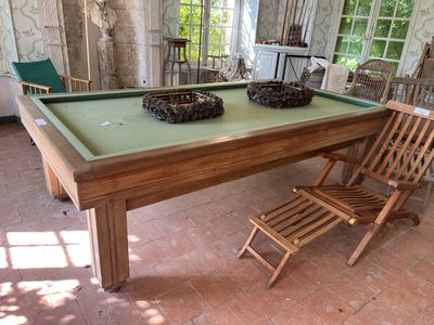 une table de billard au milieu d'une pièce où se trouvent des chaises et une table