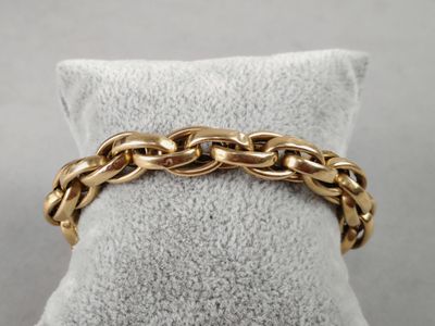 a close up of a gold chain bracelet on a pillow