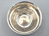 silver plated bowl on a gray surface with a small hole in the middle of the bowl