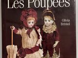 des livres sur les poupées et des poupées exposées sur un mur blanc
