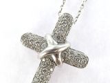 a close up of a silver cross on a chain on a white background