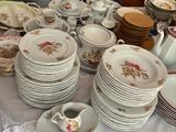 de nombreuses assiettes et tasses sur une table, avec un homme debout à l'arrière-plan