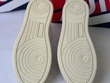 pair of white shoes sitting on top of a box next to a pair of red and white shoes