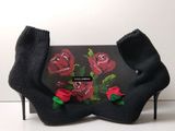 a black purse with red roses on it and a pair of black socks