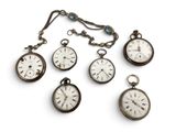 Plusieurs montres de poche anciennes sont exposées sur un support blanc