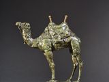 une statue en bronze représentant un chameau avec une selle sur le dos