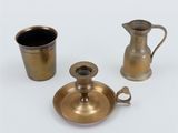 three pieces of brassware including a pitcher, a cup and a saucer