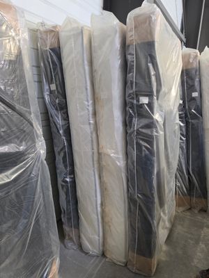 many mattresses wrapped up in plastic bags in a warehouse
