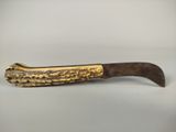 a gold plated knife with a curved handle on a white surface