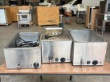 trois casseroles en acier inoxydable posées sur une table dans un entrepôt
