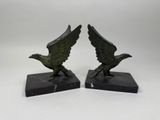 une paire de serre-livres en bronze représentant des aigles, posés sur des socles en marbre