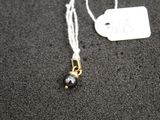 a necklace with a black bead and a white tag on it