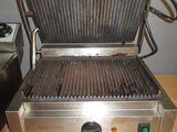 a grill that is on a table with a person holding a knife
