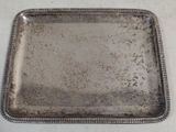 assiette rectangulaire en argent plaqué, avec un bord festonné sur fond blanc