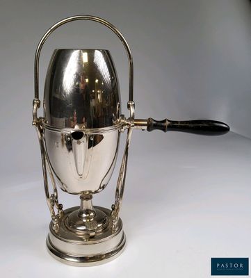 une cafetière en argent avec une anse, posée sur une table blanche