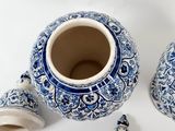 two blue and white vases with lids on a white surface