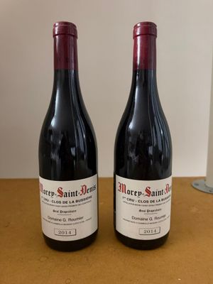 two bottles of red wine sitting on a table next to each other