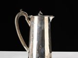 a silver coffee pot sitting on a table with a black background