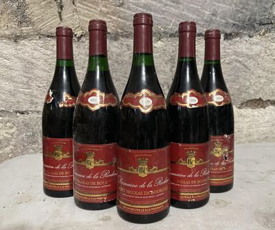 six bottles of wine are lined up on a table in front of a stone wall