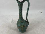 a small green vase sitting on a white surface