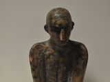 une petite statue représentant un homme assis sur une table