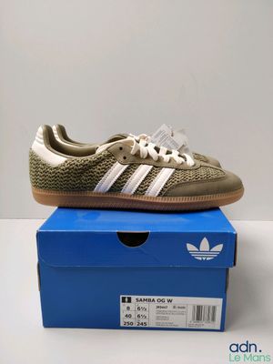 a pair of adidas trainers in gold and white on a blue box