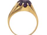 a close up of a gold ring with a purple stone