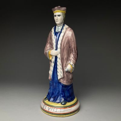 une vieille figurine représentant un homme vêtu d'une robe et d'un chapeau