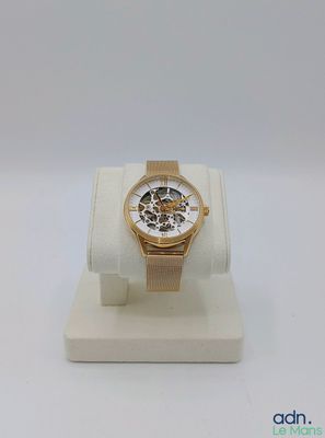 un gros plan d'une montre posée sur un présentoir, sur une surface blanche