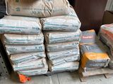 many bags of cement sitting on a pallet next to a stack of boxes