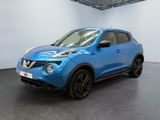 the blue nissan juke suv is parked in a showroom
