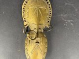 un vieux masque en laiton accroché au mur