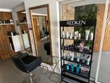 une photo d'un salon de coiffure avec un sèche-cheveux et des fauteuils