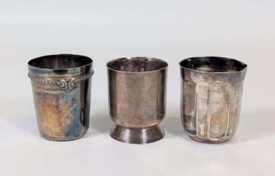 trois tasses en argent posées l'une à côté de l'autre sur une table