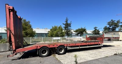 une remorque à plateau rouge garée sur un parking