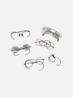 plusieurs paires de lunettes posées sur une surface blanche, sur fond blanc