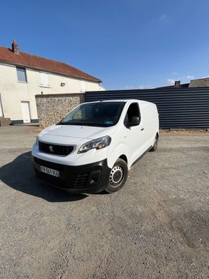 une camionnette blanche garée sur un parking à côté d'un bâtiment